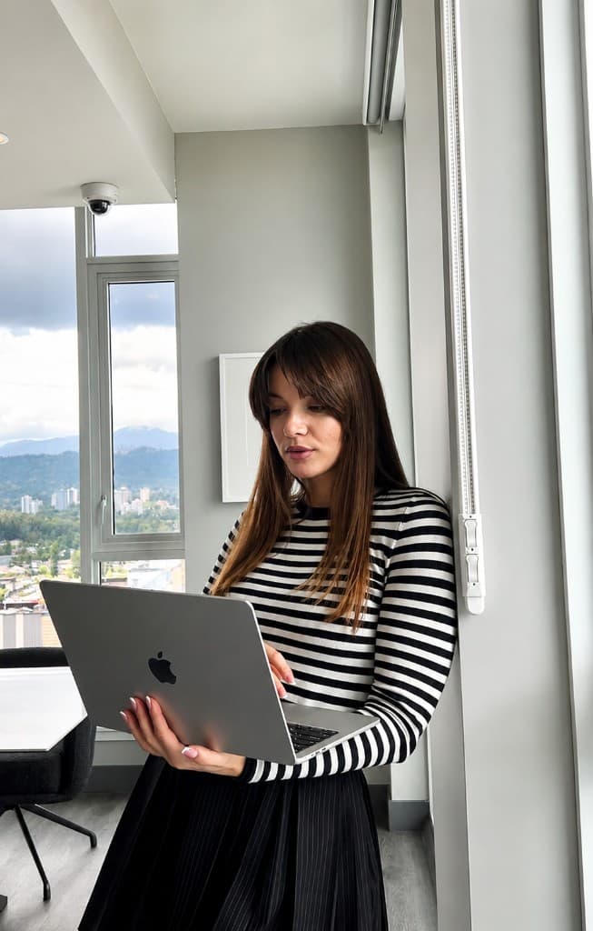 Founder reviewing project work on a laptop in a bright Vancouver workspace — clear process from kickoff to measurable results