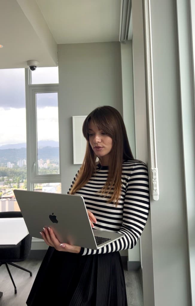 Founder reviewing project work on a laptop in a bright Vancouver workspace — clear process from kickoff to measurable results