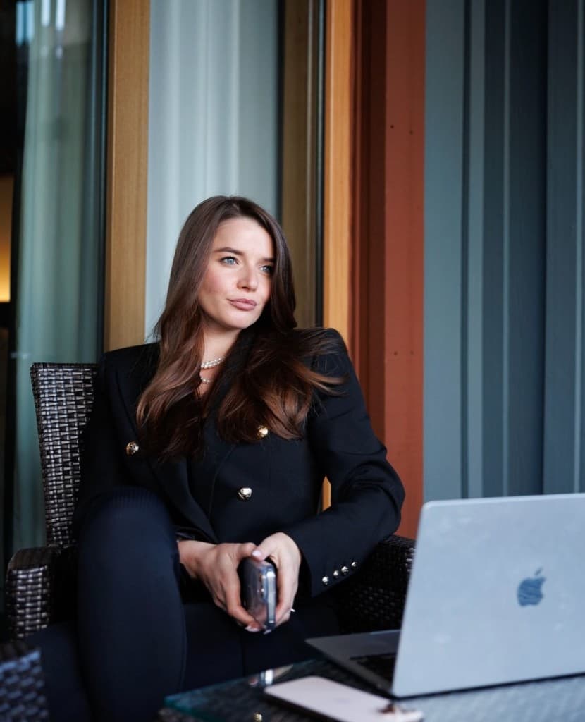 Professional woman in a black blazer at a glass table with a laptop on a modern balcony — founder and executive audience for Image Logix